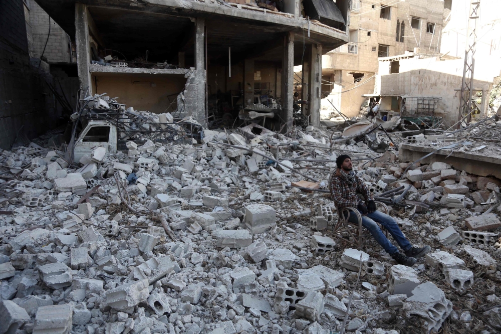 A Syrian man sits amidst the destruction in the rebel-held town of Hamouria, in the besieged Eastern Ghouta region on the outskirts of the capital Damascus, on March 9, 2018. / AFP / ABDULMONAM EASSA 