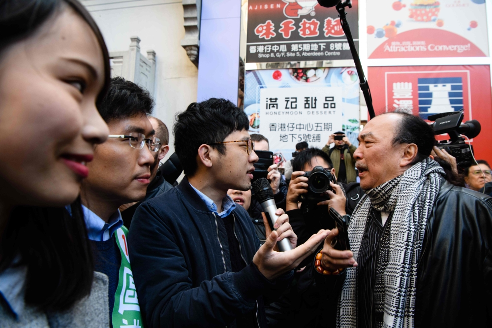 A man (R) shouts at disqualified pro-democracy lawmaker Nathan Law (C) as by-election candidate Au Nok-hin (2nd L) and disqualified pro-democracy candidate Agnes Chow (L) look on as they gather to campaign on behalf of Au for the Legislative Council by-el