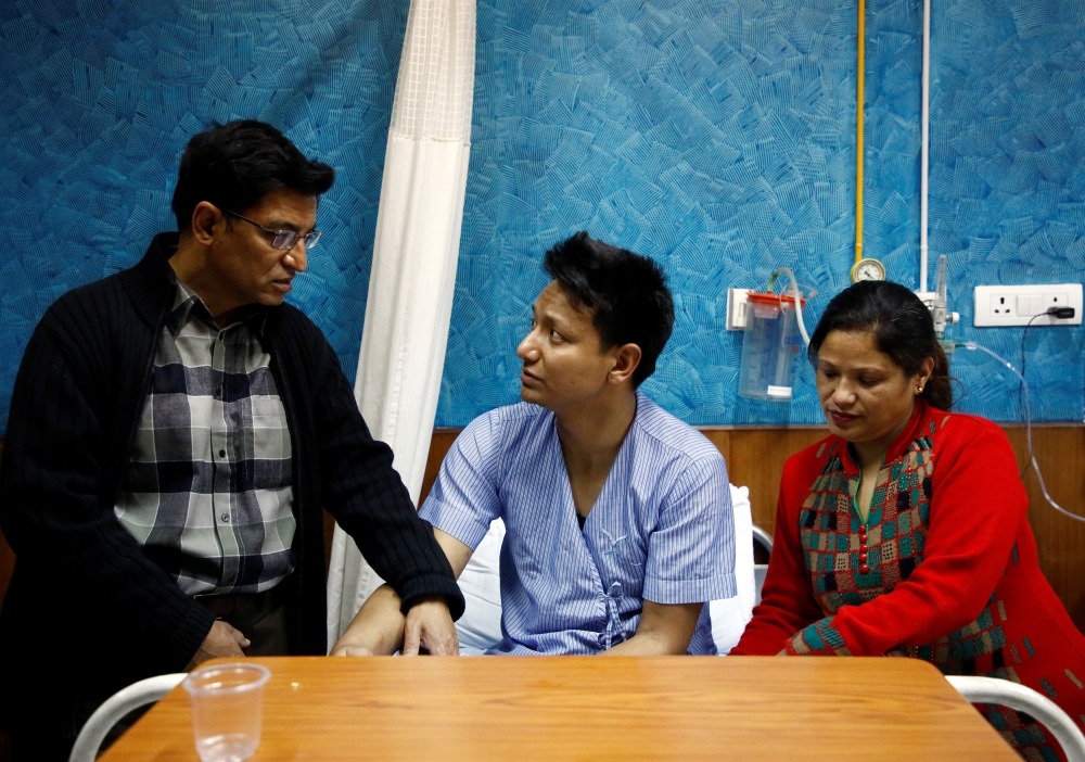 Sanam Shakya, 33, a survivor from the US-Bangla plane crash speaks with his father as his mother sits next to him while undergoing treatment at a hospital in Kathmandu, Nepal March 12, 2018. Reuters/Navesh Chitrakar