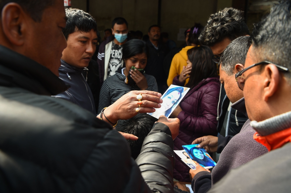 Family members of a plane crash victim hold pictures of their loved ones outside a morgue at the Teaching Hospital in Kathmandu on March 13, 2018, a day after the deadly crash of a US-Bangla Airlines plane at the international airport. AFP / Prakash Mathe