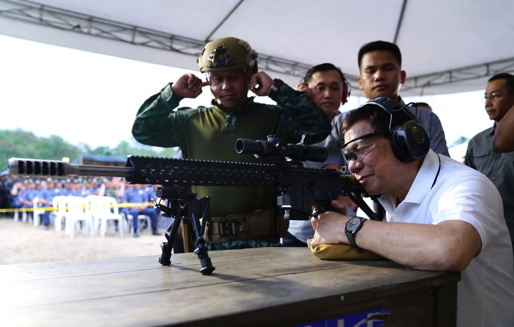 (FILES) A file photo taken and released by Presidential Photographers Division (PPD) on March 1, 2018, shows President Rodrigo Duterte firing a few rounds with a sniper rifle during the opening ceremony of the National Special Weapons and Tactics (SWAT) C