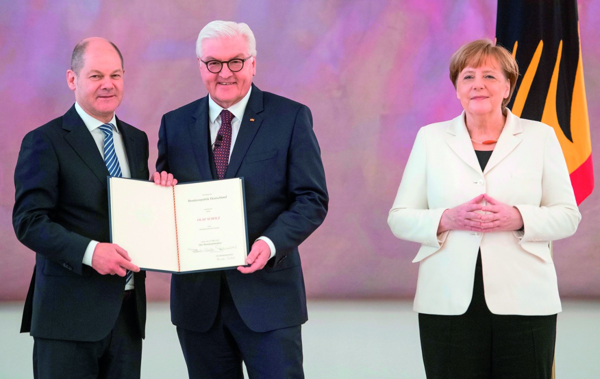 German President Frank-Walter Steinmeier (C) hands over the certificate of appointment to the new German Finance Minister and Vice-Chancellor Olaf Scholz as German Chancellor Angela Merkel looks on on March 14, 2018 at Bellevue Palace in Berlin. AFP / Ste