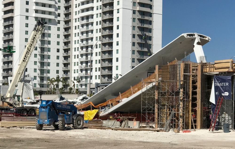A crane is seen near a newly installed pedestrian bridge, that collapsed, over a six-lane highway in Miami, Florida on March 15, 2018, crushing a number of cars below and reportedly leaving several people dead. AFP TV / Antoni Belchi 