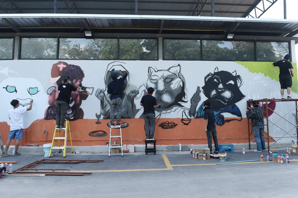  Graffiti artists spray paint a mural of panthers, in protest against the illegal wildlife poaching by construction tycoon Premchai Karnasuta, in Bangkok on March 16, 2018.  AFP / Lillian Suwanrumpha