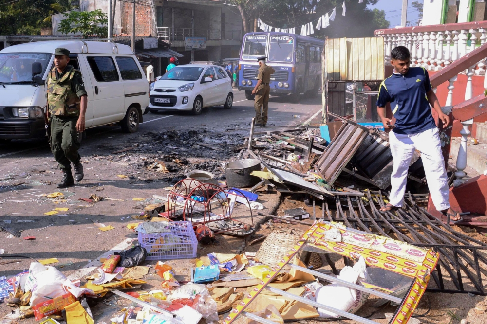 (FILES) In this file photo taken on March 6, 2018, police commandos patrol next to debris from a damaged shop in the central district of Kandy, after a state of emergency was declared. AFP