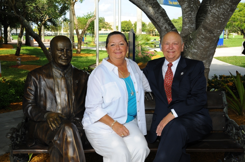 Wayne and Marti Huizenga sit  next to a new Huizenga bronze statue (Photo courtesy: nsunews.nova.edu) 