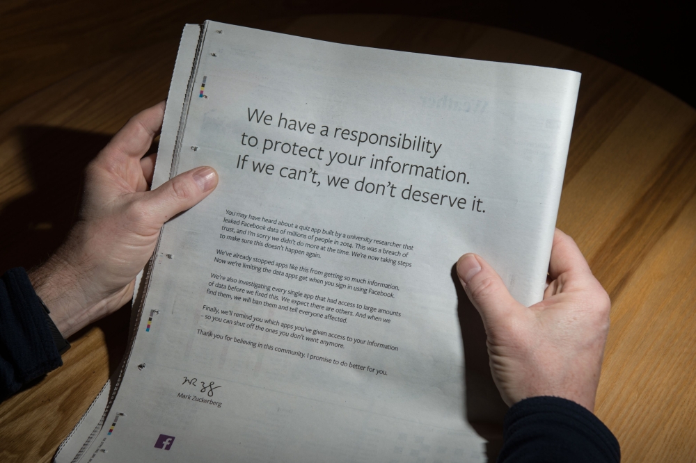 A man reads a full-page advertisement, taken out by Mark Zuckerberg, the chairman and chief executive officer of Facebook to apologise for the large-scale leak of personal data from the social network, on the backpage of a newspaper, in Ripon, England on 