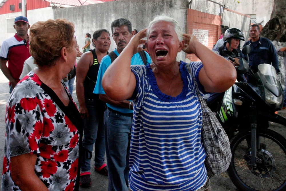 A relative of a prisoner cries in front of a police station in Valencia on March 28, 2018, after a fire engulfed police holding cells that resulted in the deaths of 68 people.  AFP / Katherine ORTIZ
