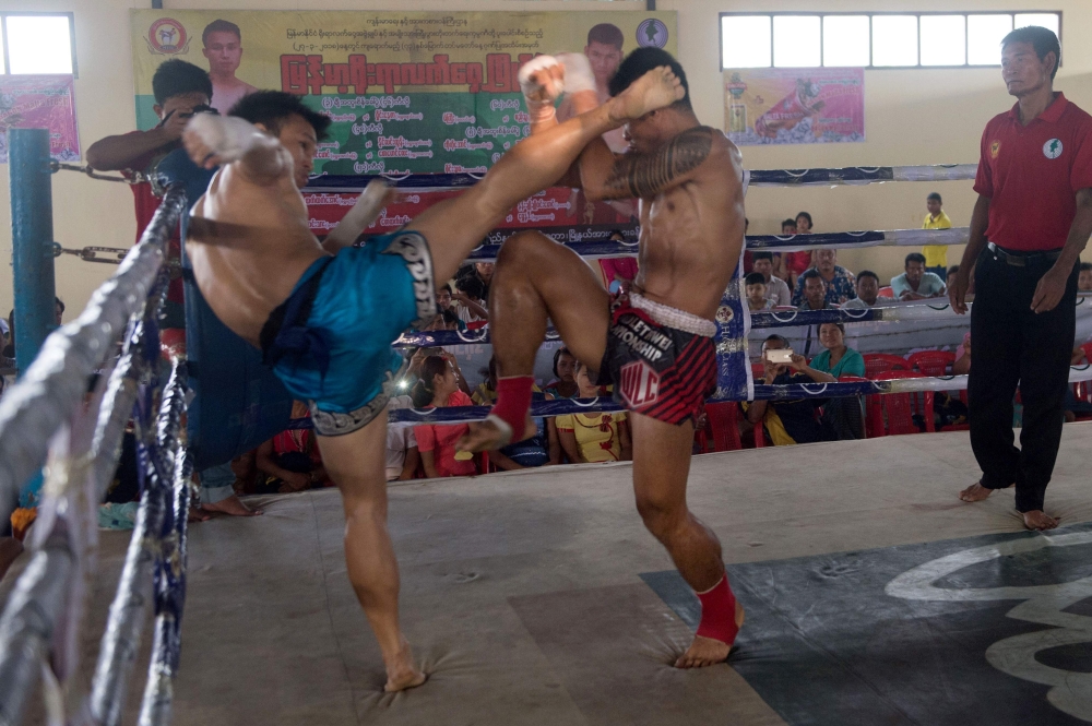 In this photograph taken on March 27, 2018, fighters Thway Thit Win Hlaing (L) and Saw Ba Oo (R), representing Myanmar's Karen state, battle during a ground-breaking Lethwei competition in the Maungdaw district of violence-rocked Rakhine state, close to t