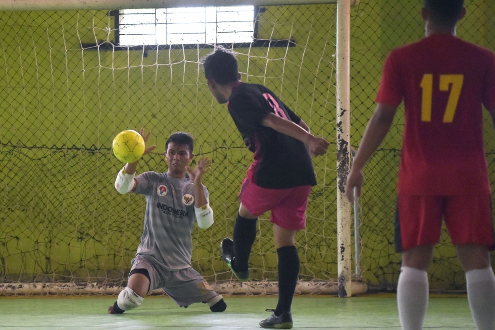 This picture taken on February 3, 2018 shows goalkeeper Eman Sulaeman (L) attempting a save during a futsal (five-a-side indoor football) match in Indramayu, West Java. AFP / Adek Berry 