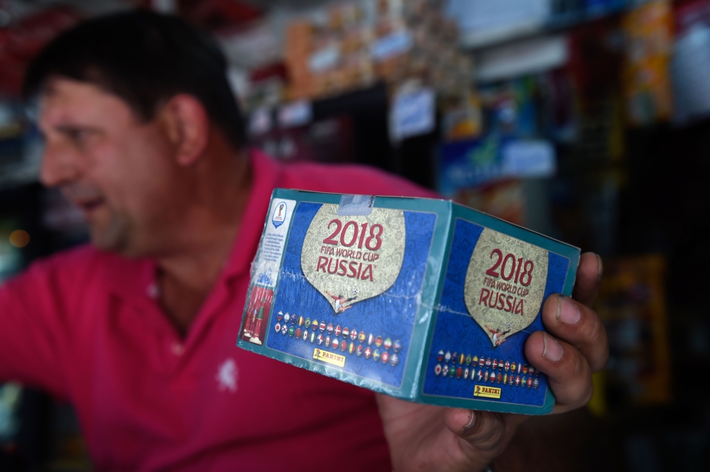 A newsstand vendor shows a box of collectible trading cards of the album Russia 2018 in Caracas on April 2, 2018. Due to the economic crisis in Venezuela, fans are not able to collect the FIFA World Cup Russia 2018 picture cards. AFP / Federico Parra 