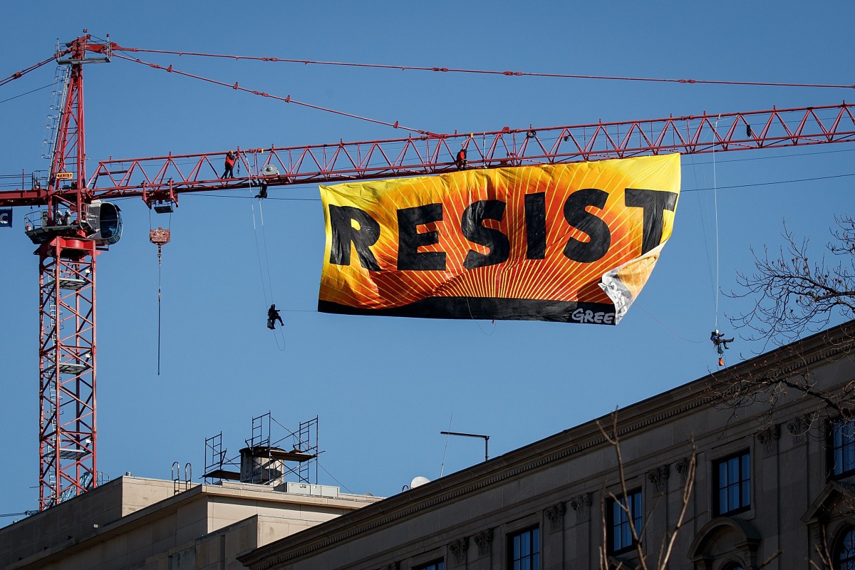 Protesters unfurl a banner atop a crane at the construction site of the former Washington Post office building, January 25, 2017. (Drew Angerer / Getty Images / AFP) 