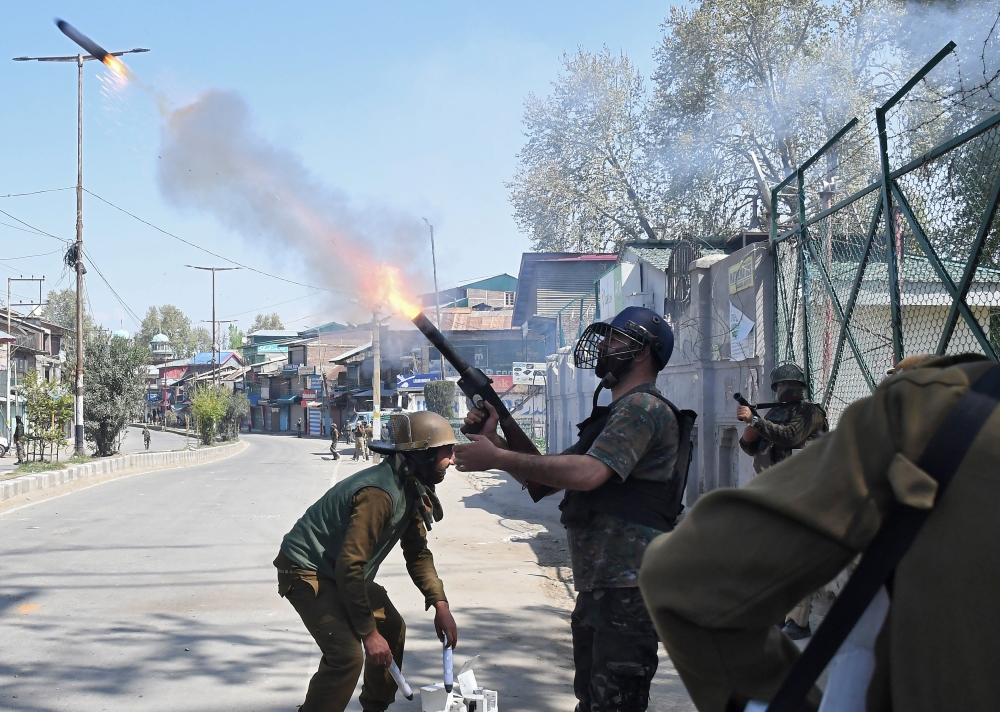 An Indian policeman fires a tear smoke shell towards protesters during the funeral of Mussavir Ahmed Wani, a suspected militant, who according to local media reports was killed in a gunbattle with Indian security forces on Friday, in south Kashmir's Pulwa