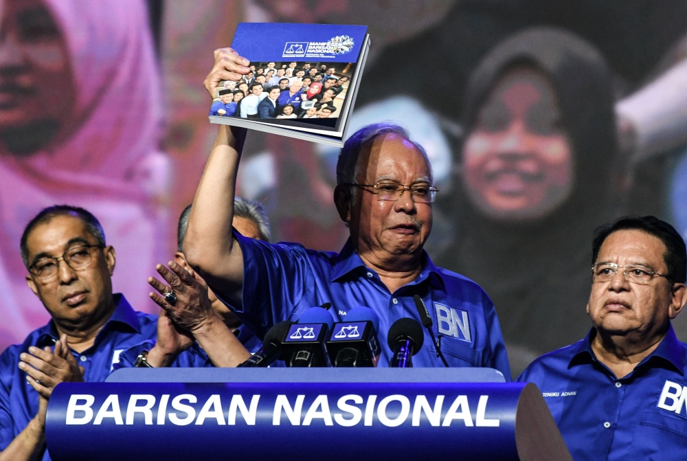 Malaysian Prime Minister Najib Razak (C) gestures as he holds a copy of his coalition's election manifesto next to other party members ahead of the upcoming polls during a National Front coalition or Barisan Nasional rally, in Kuala Lumpur on April 7, 201