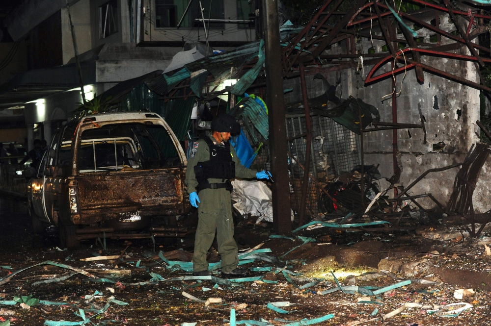 A member of a Thai police bomb squad inspects the site of a bomb blast in Sungai Kolok, Narathiwat province, on April 9, 2018.  / AFP / Madaree TOHLALA 