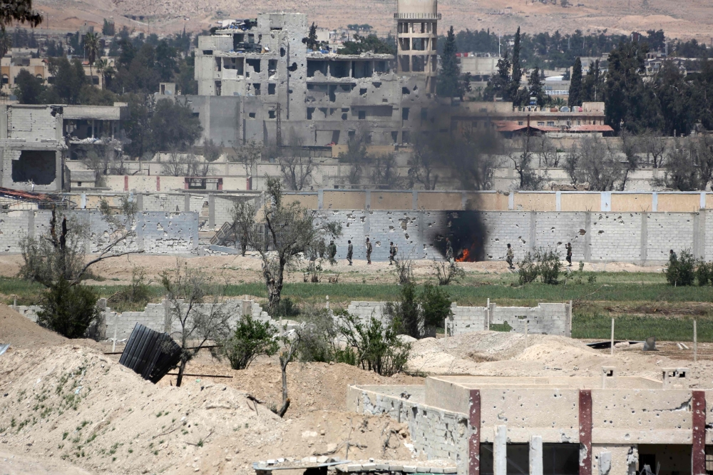 A picture taken on April 8, 2018, shows smoke billowing as Syrian Army soldiers advance in agricultural land on the eastern outskirts of Douma, as they continue their fierce offensive to retake the last opposition holdout in Eastern Ghouta.  AFP / STRINGE