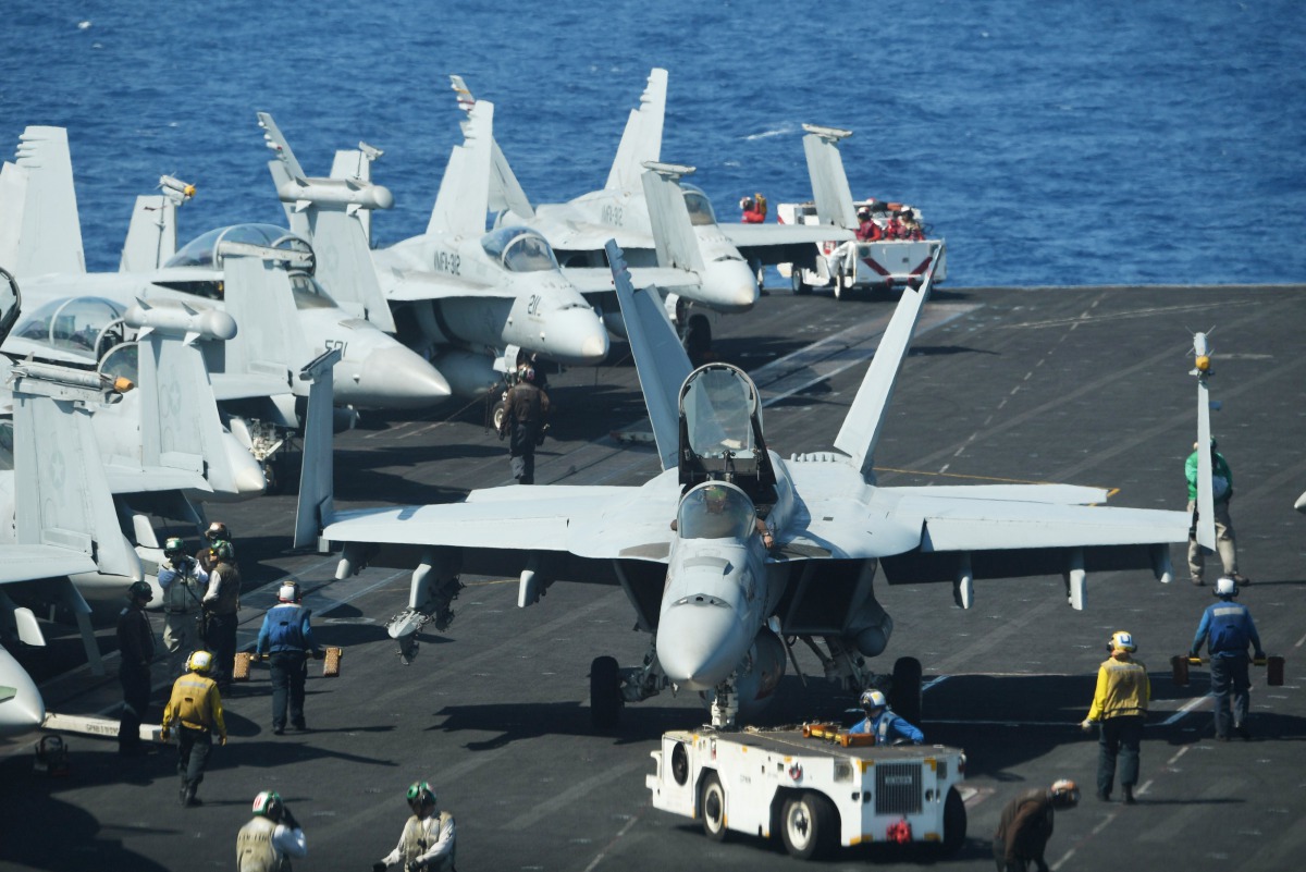 Sailors preapre FA-18 Hornet fighter jets for take off during a routine training aboard the US aircraft carrier Theodore Roosevelt in the South China Sea on April 10, 2018.  AFP / Ted Aljibe