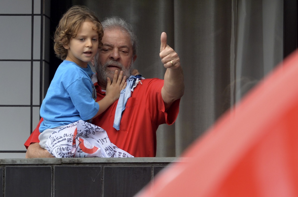 Luiz Inacio Lula da Silva holds his grandson Pedro while waves supporters from the balcony of his apartment in Sao Bernardo do Campo, some 25 km from Sao Paulo,  Brazil, on March 13, 2016. AFP / Nelson Almeida
