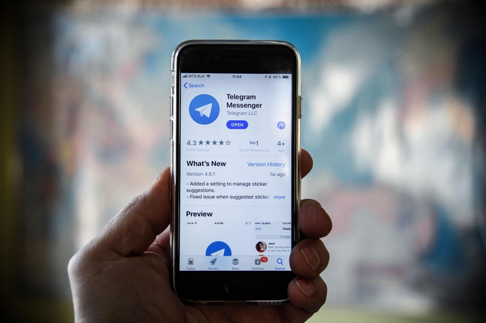 This file photo taken in Moscow shows a person posing while holding a smartphone with the Telegram messenger application on display. (AFP / Alexander NEMENOV)