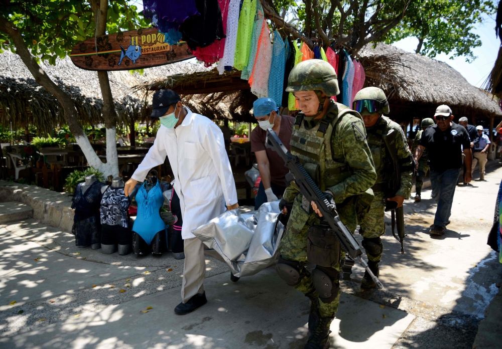 Forensic personnel and Mexican soldiers carry the corpse of a murdered man, who was found in Caletilla Beach, Acapulco, Guerrero state, Mexico on April 15, 2018.   AFP / Francisco Robles
