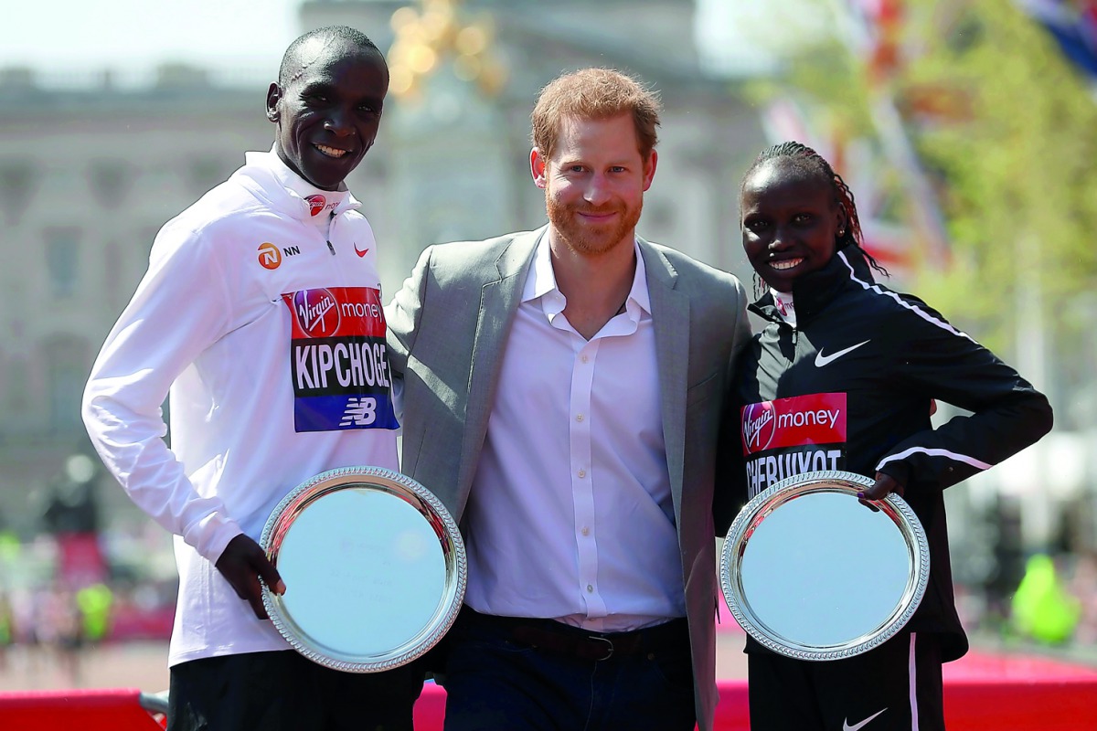 Britain's Prince Harry (C) poses with elite men's race winner Kenya's Eliud Kipchoge (L) and elite women's race winner Kenya's Vivian Cheruiyot during the trophy ceremony of the 2018 London Marathon in central London on April 22, 2018. AFP / Daniel Leal-O