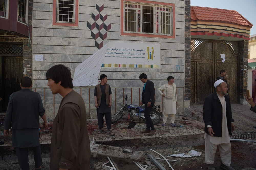 Afghan residents inspect the site of a suicide bombing outside a voter registration centre in Kabul on April 22, 2018.  / AFP / SHAH MARAI 