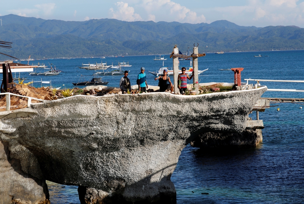 Workers stand on a rock formation that was turned into a mini park by West Cove resort, two days before the temporary closure of the holiday island Boracay in the Philippines April 24, 2018. Picture taken April 24, 2018. REUTERS/Erik De Castro