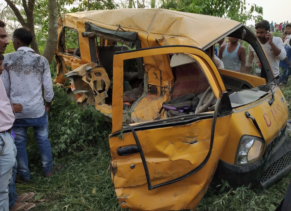 Onlookers gather around the mangled remains of a school bus after it was hit by a train in Kushinagar district in India's Uttar Pradesh state on April 26, 2018. AFP 