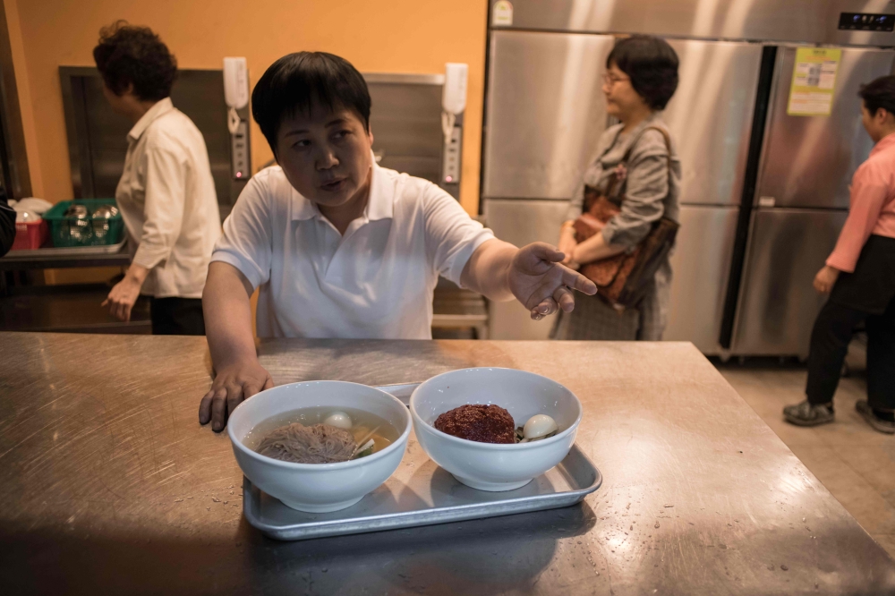 A waiter prepares to serve a 'Pyongyang naengmyeon' a cold noodle dish at the Nampo Myeonok noodle bar restaurant in Seoul on April 28, 2018. AFP / Ed JONES