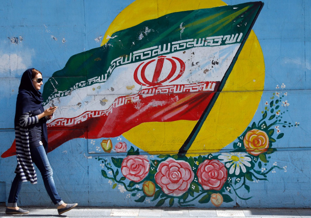 An Iranian woman walks past a mural of the Iranian flag in the capital, Tehran on October 14, 2017. (AFP) 