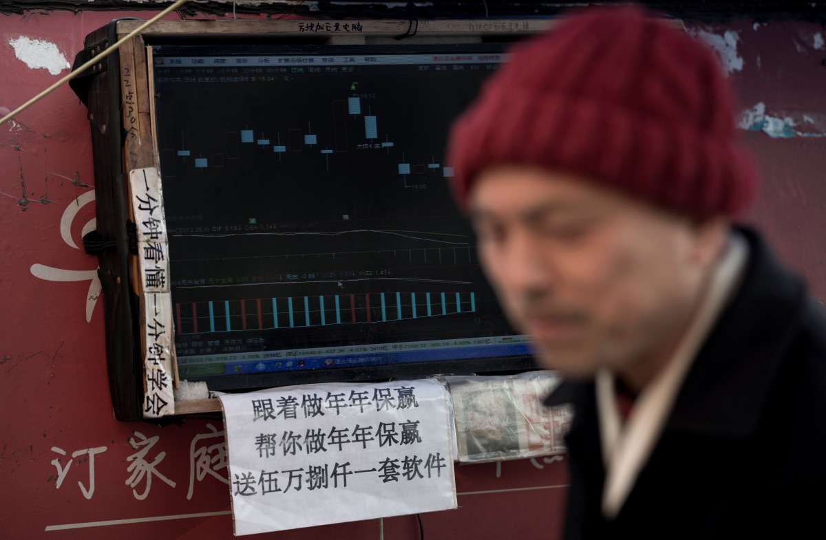 This picture taken on March 25, 2018 shows Shen Yuxi (R), who peddles stock analysis software, next to the screen of his computer showing financial data at Shanghai's open-air investment bazaar.  AFP / Johannes Eisele