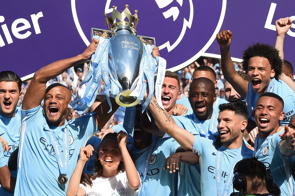 Manchester City's captian, Belgian defender Vincent Kompany (2nd L) and Manchester City's Argentinian striker Sergio Aguero lift up the Premier League trophy on the pitch after the English Premier League football match between Manchester City and Huddersf