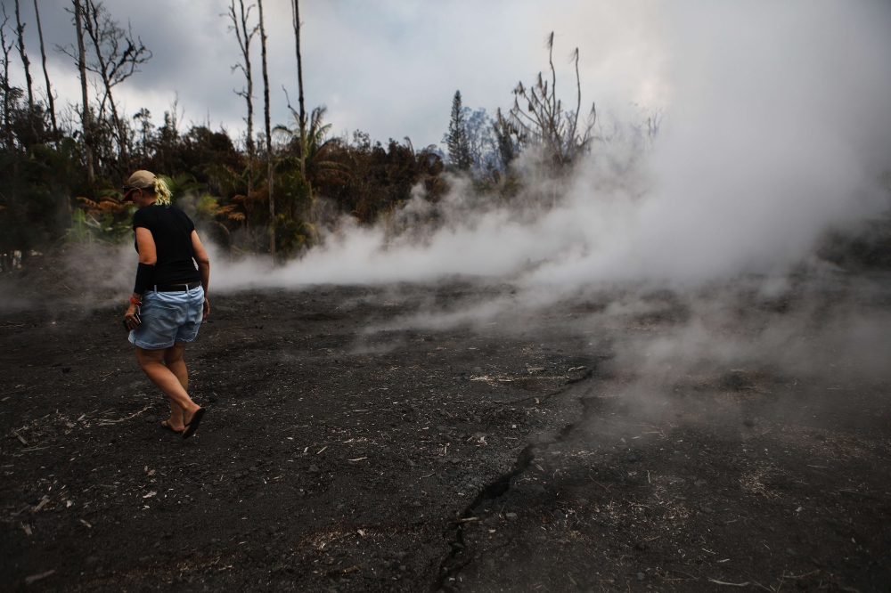 Resident Stacy Welch inspects fissures located near her home, which remains standing, in the Leilani Estates neighborhood in the aftermath of eruptions from the Kilauea volcano on Hawaii's Big Island on May 7, 2018 in Pahoa, Hawaii. Mario Tama/Getty Image