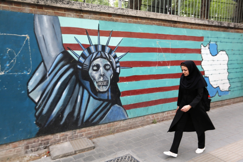 An Iranian woman walks past a mural on the wall of the former US embassy in the Iranian capital Tehran on May 8, 2018.  AFP / Atta Kenare