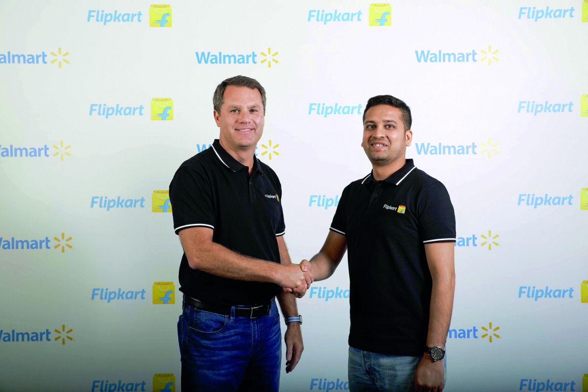 Walmart CEO Doug McMillon (L) and Flipkart co-founder and CEO Binny Bansal shaking hands at an event in Bangalore on May 9, 2018, as a deal was announced for Walmart to buy a stake in Flipkart. AFP photo / Walmart