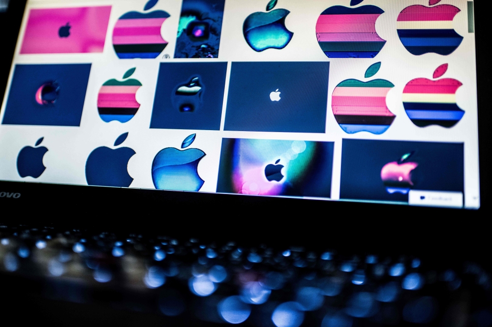 (FILES) In this file photo taken on March 23, 2018 shows Apple logos on a computer screen in Beijing. AFP / NICOLAS ASFOURI