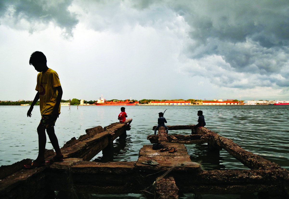 A boy walks through a damaged jetty as pre-monsoon clouds gather above the Vembanad Lake in Kochi, India, May 11, 2018. Reuters/Sivaram V



