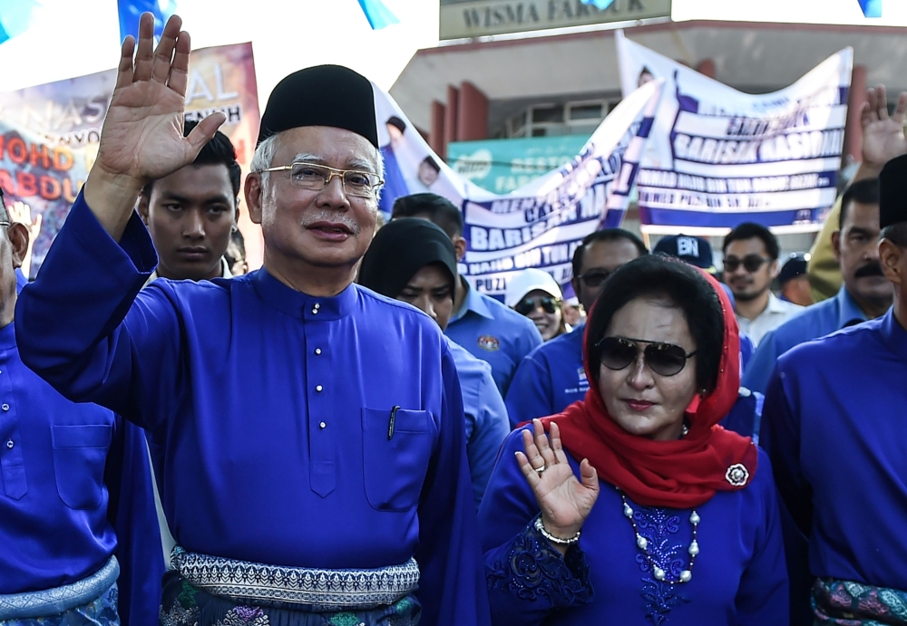 File photo of Malaysia's then-Prime Minister Najib Razak (L) and his wife Rosmah Mansor (R) wave as they arrive at the nomination centre to hand over election documents in Pekan, April 28, 2018. / AFP / Mohd RASFAN 