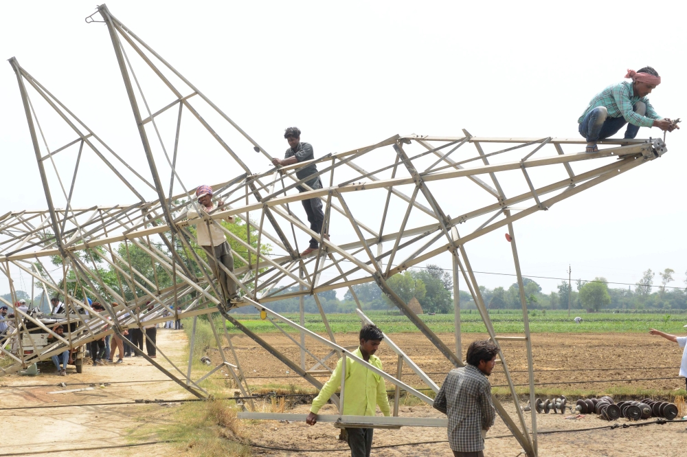 Indian workers remove a damaged electrical transmission tower which collapsed in a storm on May 12 in Ibban Kallan village on the outskirts of Amritsar on May 13, 2018. / AFP / NARINDER NANU