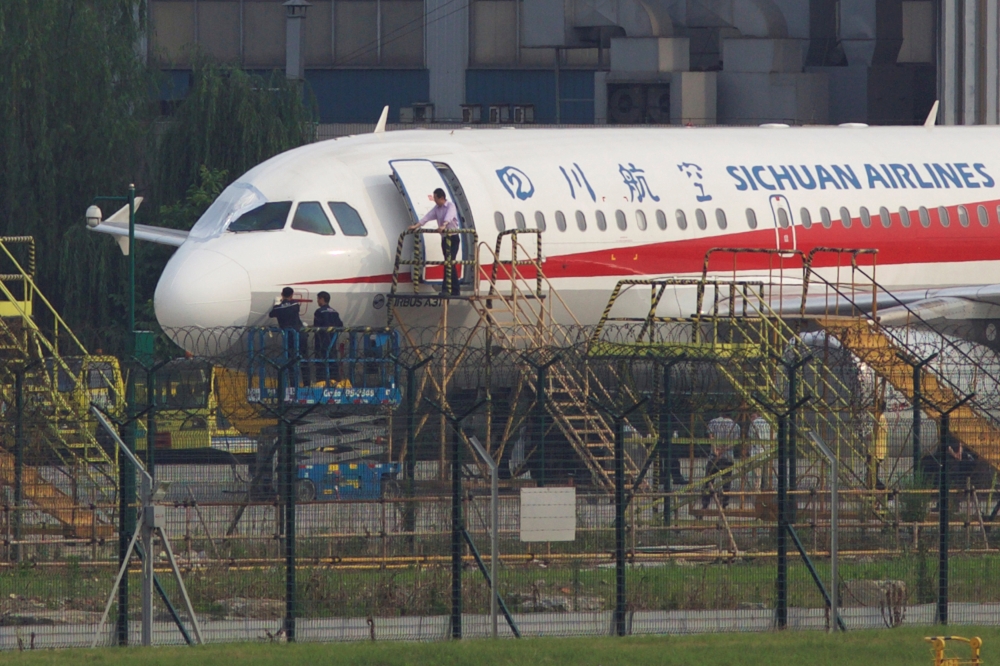 Workers inspect a Sichuan Airlines aircraft that made an emergency landing after a windshield on the cockpit broke off, at an airport in Chengdu, Sichuan province, China May 14, 2018. REUTERS/Stringer