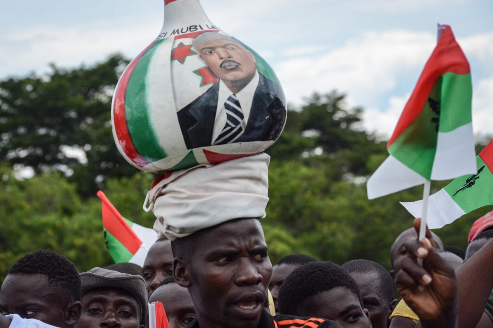 A supporter of Burundi’s ruling CNDD-FDD party, balances a gourd on his head with the image of the Burundian President Pierre Nkurunziza, during a rally three days prior to a referendum on a controversial constitutional reform on May 14, 2018 in Bujumbura