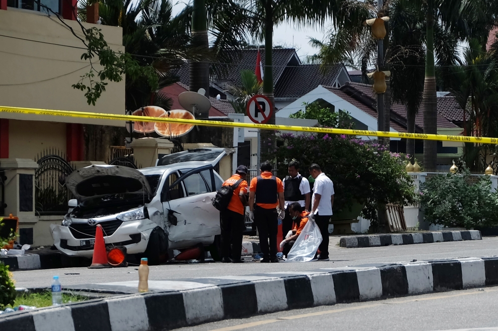 Indonesian policemen examine a car used by attackers outside the police headquarter in Pekanbaru, Riau following attacks on May 16, 2018. AFP / DEDY SUTISNA