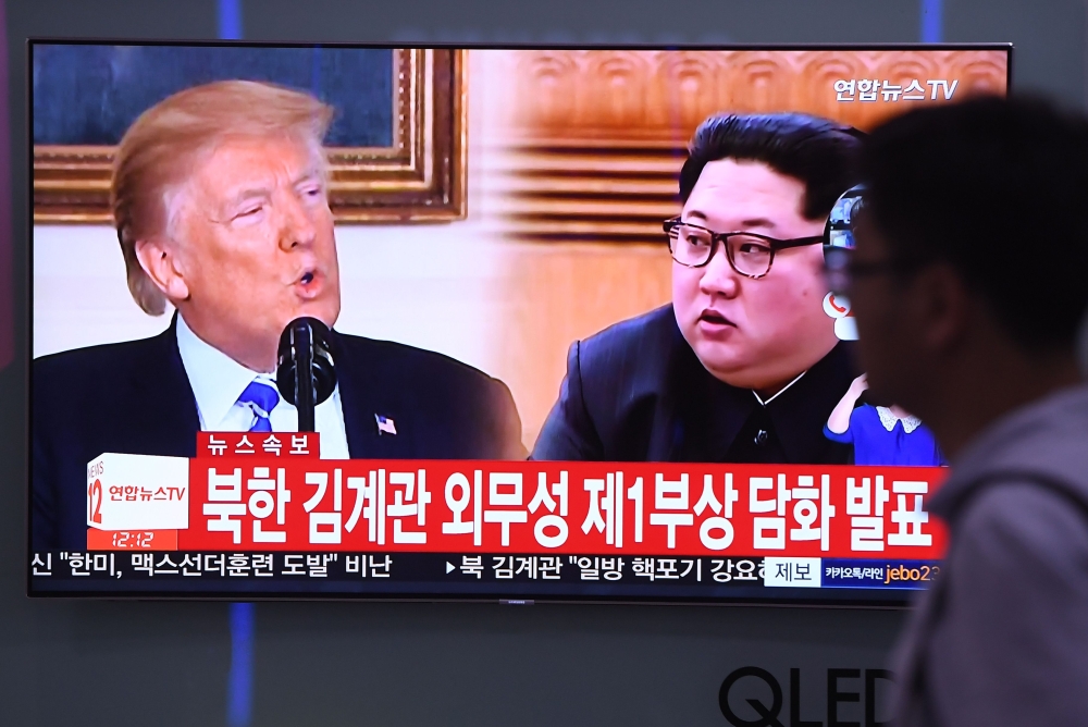 A man walks past a television news screen showing North Korean leader Kim Jong Un (R) and US President Donald Trump (L) at a railway station in Seoul on May 16, 2018.  / AFP / Jung Yeon-je 