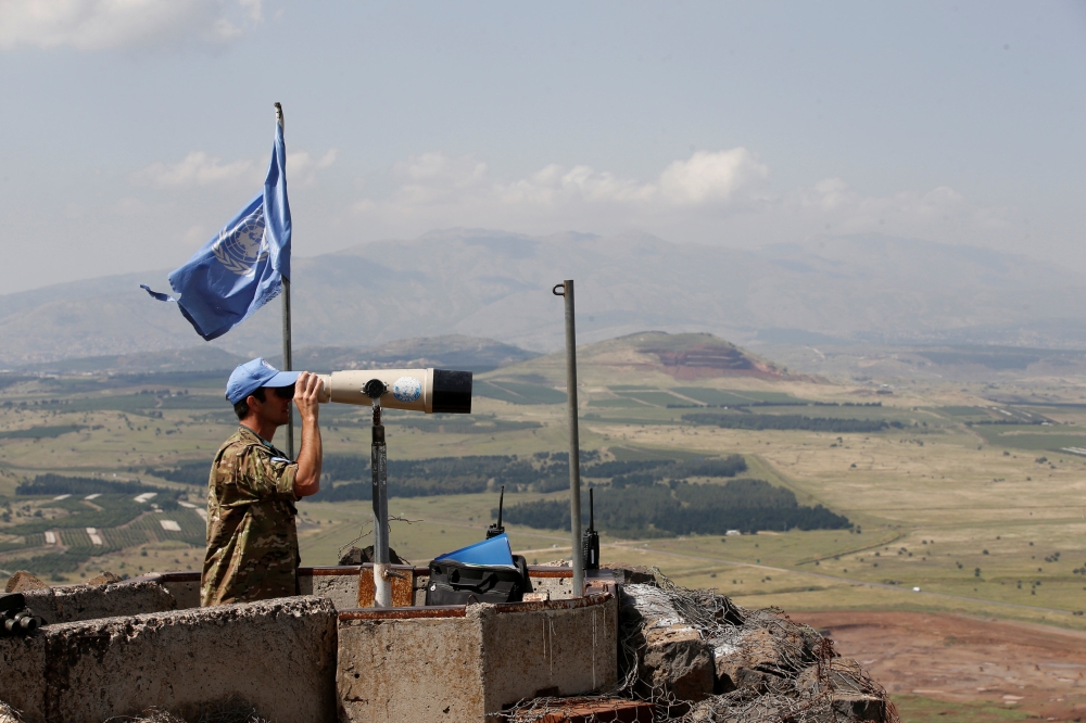 A United Nations Truce Supervision Organisation military observer uses binoculars near the border with Syria in the Israeli-occupied Golan Heights, Israel May 11, 2018. Reuters/Baz Ratner