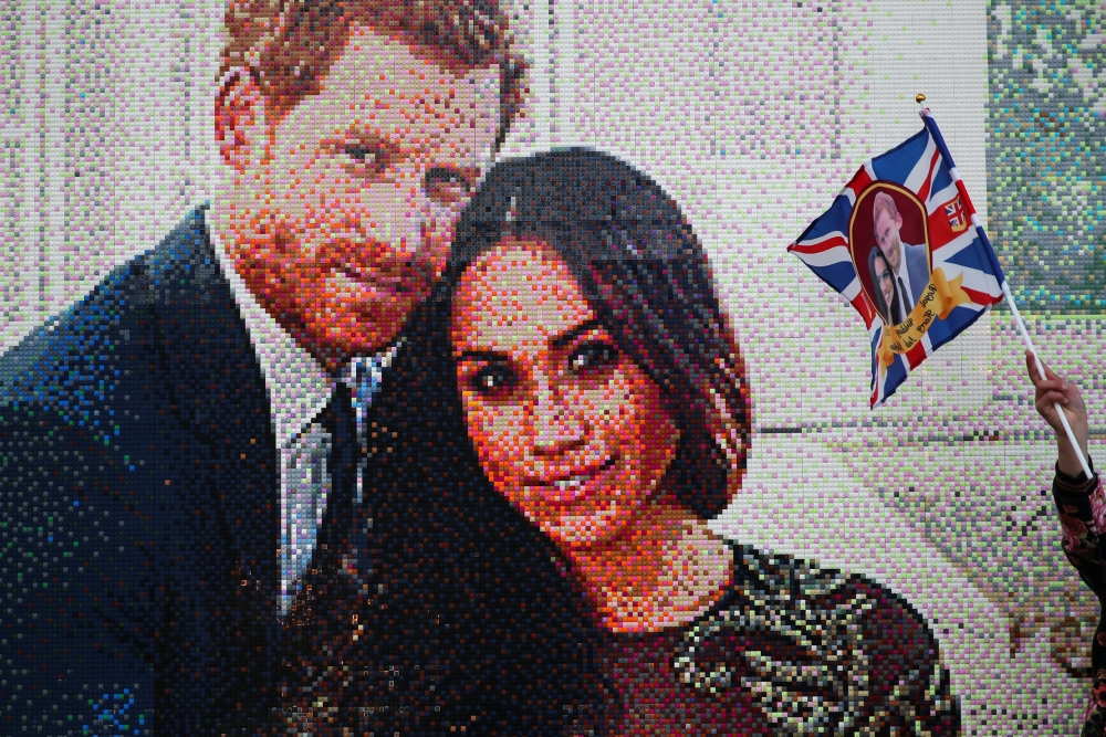 A girl waves a flag next to a LEGO brick mosaic of Britain's Prince Harry and Meghan Markle in Windsor, Britain May 18, 2018. REUTERS/Marko Djurica