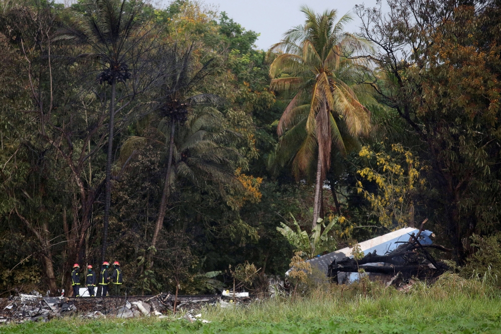 Firefighters work at the wreckage site of a Boeing 737 plane that crashed in the agricultural area of Boyeros, around 20 km (12 miles) south of Havana, shortly after taking off from Havana's main airport in Cuba, May 18, 2018. REUTERS/Alexandre Meneghini 