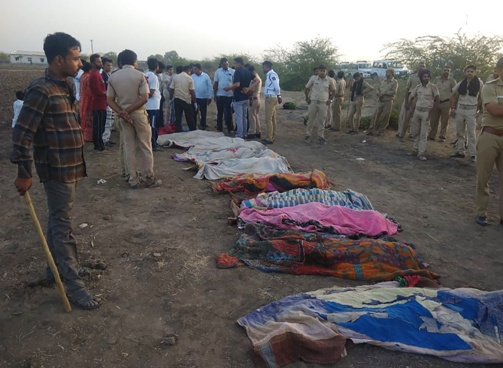 Indian police stand near the bodies of some of the victims of an accident on the Ahmedabad-Bhavnagar highway in Bavniyari village on May 19, 2018.   AFP / STR
