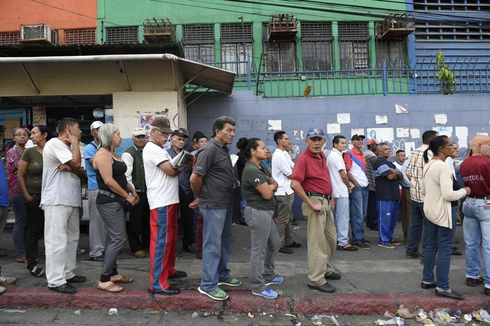 :Venezuelans queue outside a polling station as they wait to cast their vote during the presidential elections in Caracas on May 20, 2018 . AFP / Federico Parra
