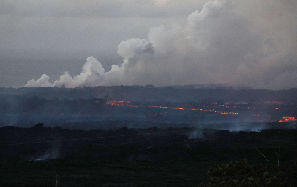 Lava from a Kilauea volcano fissure (C) flows toward the ocean on Hawaii's Big Island on May 20, 2018 in Kapoho, Hawaii.  Mario Tama/Getty Images/AFP