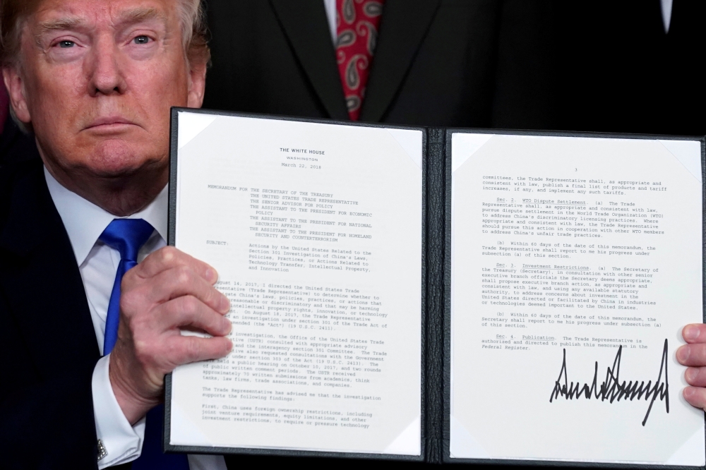 FILE PHOTO: US President Donald Trump holds a signed memorandum on intellectual property tariffs on high-tech goods from China, at the White House in Washington, US March 22, 2018. Reuters/Jonathan Ernst/File Photo